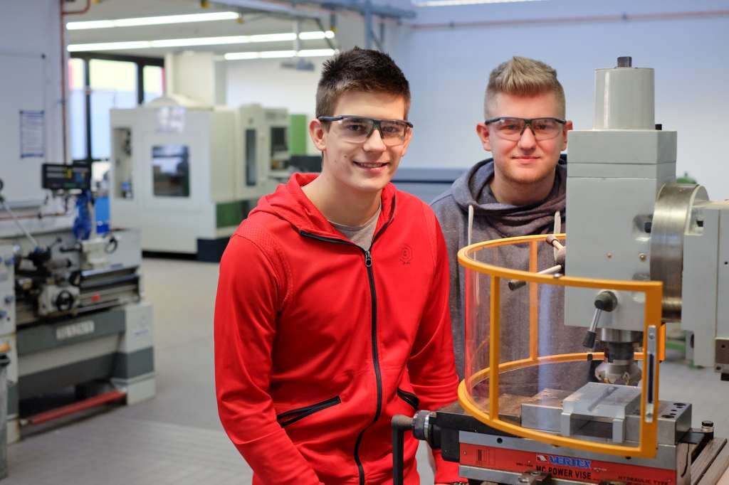 Zwei Lernende an einer Werkzeugmaschine in der Werkstatt des Berufskollegs