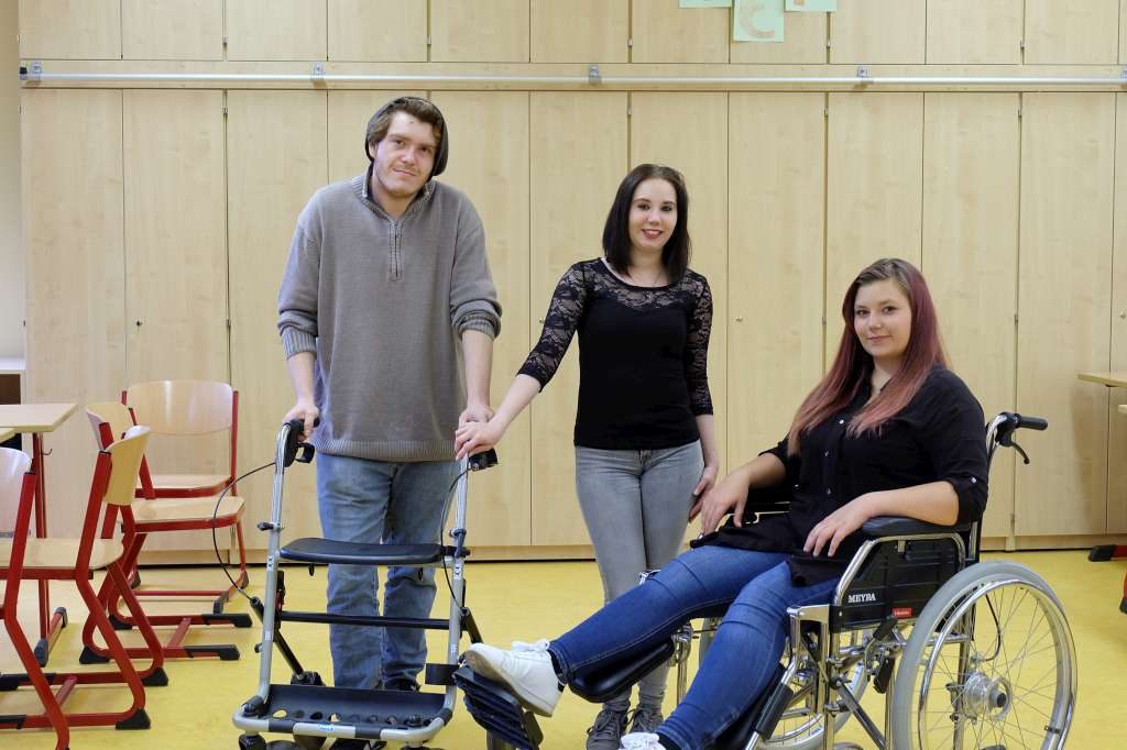 Drei Lernende üben den Umgang mit Rollator und Rollstuhl
