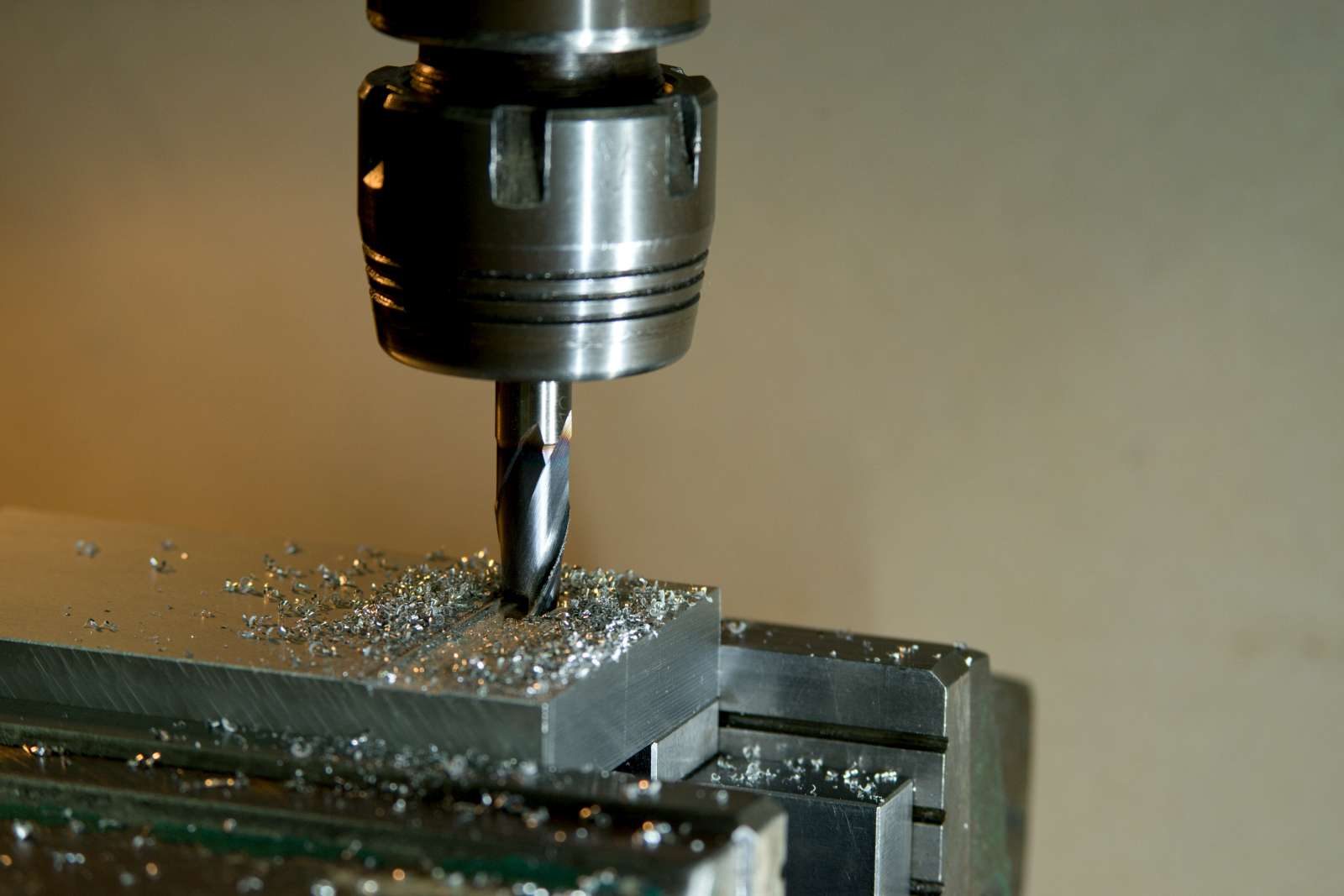 Ein Bohrer bearbeitet ein Metallteil, dabei fallen Späne